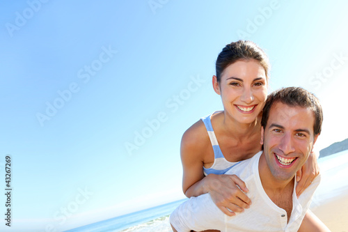 Foto: Man carrying girlfriend on his back at the beach Man carrying girlfriend on his back at the beach