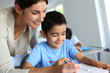 Teacher helping young boy with writing lesson