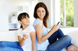 Mother and daughter using mobile phone at home