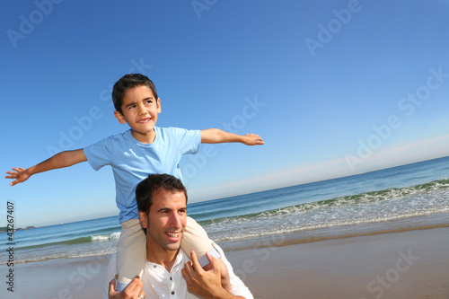 Foto: Father holding son on his shoulders at the beach Father holding son on his shoulders at the beach