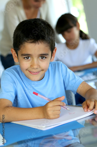 Photo: Portrait of smilng young boy sitting in classroom Portrait of smilng young boy sitting in classroom