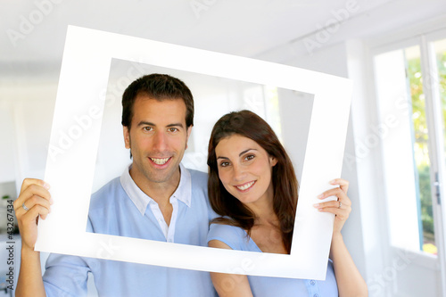 Photo: Closeup of cheerful couple looking through frame Closeup of cheerful couple looking through frame