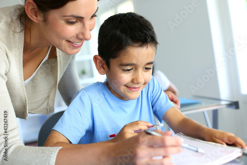 Photo: Teacher helping young boy with writing lesson Teacher helping young boy with writing lesson