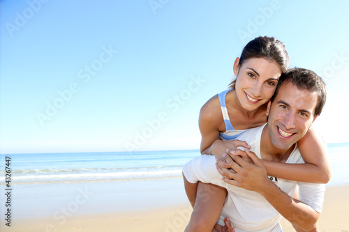 Foto: Man carrying girlfriend on his back at the beach Man carrying girlfriend on his back at the beach