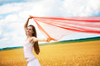 Girl with a red cloth catches wind in the yellow field