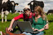 Young couple farmers in field with cows