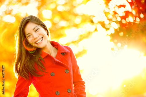Photo: Autumn red trench coat woman in sunny tree leaves Autumn red trench coat woman in sunny tree leaves