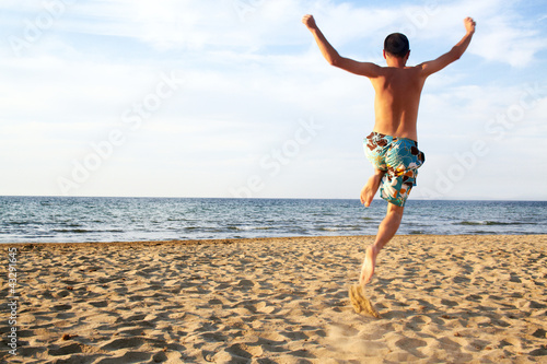 Photo: sporty young man jumping on beach sporty young man jumping on beach