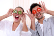 Couple holding fruit to their eyes