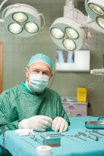 Photo: Surgeon sitting in front of surgical tools Surgeon sitting in front of surgical tools