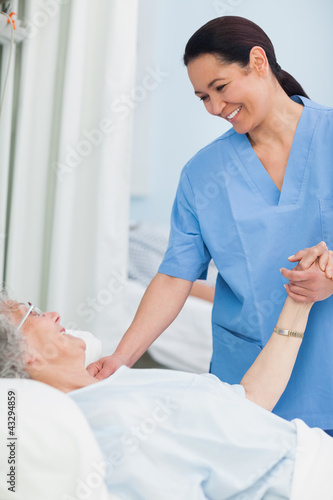 Photo: Nurse smiling to a patient while holding her hand Nurse smiling to a patient while holding her hand
