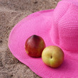 Foto: Pink hat and nectarines on the sand Pink hat and nectarines on the sand