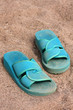 Foto: Green flip-flops on a sandy beach Green flip-flops on a sandy beach