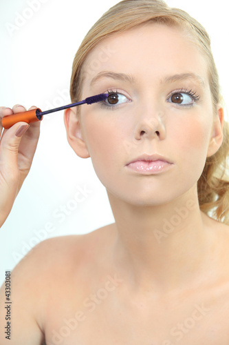 Photo: Young woman applying blue mascara Young woman applying blue mascara