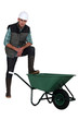 Tradesman with his foot propped on a wheelbarrow