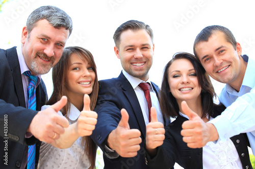 Photo: Successful young business people showing thumbs up sign Successful young business people showing thumbs up sign
