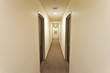 Long corridor with hotel room doors and exit sign