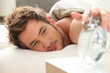 Man in bed turning off alarm