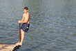 Teenage boy jumping in the river from the dock