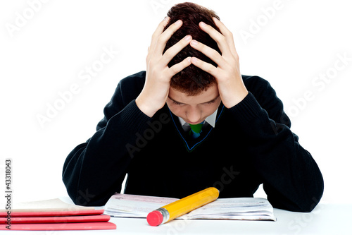 Photo: Confused student holding his head in classroom Confused student holding his head in classroom