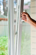 person opens a window with mosquito net