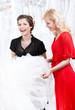 Two girls discuss the wedding dress hesitating about fitting