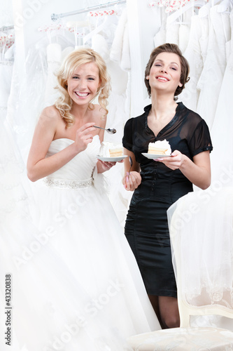 Photo: Laughing shop assistant and the bride eat a delicious cake Laughing shop assistant and the bride eat a delicious cake