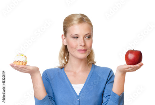 Photo: Pretty woman makes a tough choice between cake and apple Pretty woman makes a tough choice between cake and apple