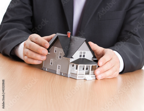 Photo: Real estate concept - businessman hands architectural model Real estate concept - businessman hands architectural model