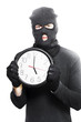 Photo: Male criminal in mask holding a clock Male criminal in mask holding a clock