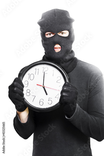 Photo: Male criminal in mask holding a clock Male criminal in mask holding a clock