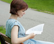 Foto: young girl sitting on a bench and reading book young girl sitting on a bench and reading book