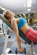 Mixed race woman lifting weights in health club