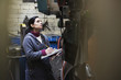 Hispanic worker with clipboard working in factory