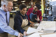 Foreman and workers looking at paperwork in factory