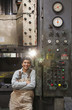 Mixed race worker standing near factory control panel