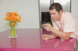 Hispanic man leaning on counter text messaging on cell phone