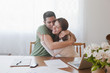 Hispanic couple paying bills and hugging