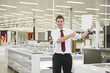 Caucasian salesman standing in home supply store holding blank card