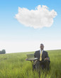 Black businessman sitting at desk in field with laptop