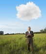 Black businessman standing in field text messaging on cell phone