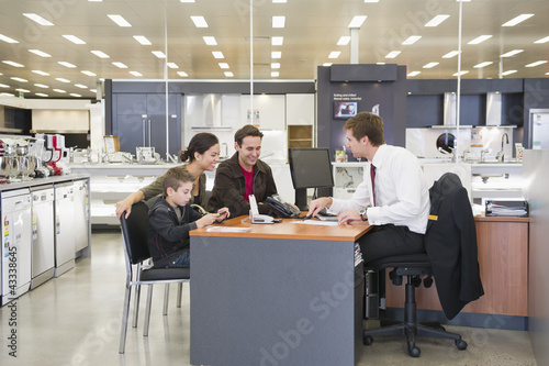 Photo: Salesman talking to Hispanic family in home supply store Salesman talking to Hispanic family in home supply store