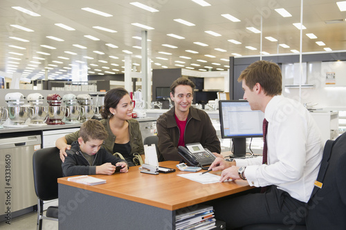 Photo: Salesman talking to Hispanic family in home supply store Salesman talking to Hispanic family in home supply store