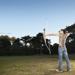 Mixed race archer shooting arrow in field