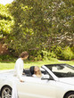 Caucasian man helping wife into convertible