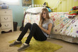 Mixed race teenager sitting on bedroom floor