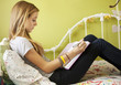 Mixed race teenager sitting on bed doing homework