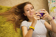 Mixed race teenager laying on floor text messaging on cell phone