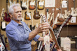 Hispanic craftsman looking at guitars in shop