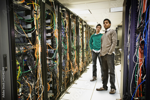 Photo: Businessmen standing together in server room Businessmen standing together in server room